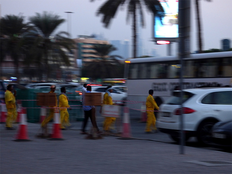 A line of workers in yellow overalls boarding a white bus 