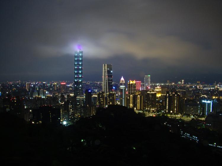 The skyline of Taipei with the Taipei 101 skyscraper piercing through the low clouds at night
