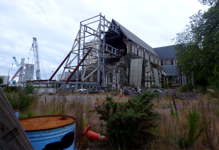 A large steel-beam construction holding up the remains of a church, with the front half completely collapsed