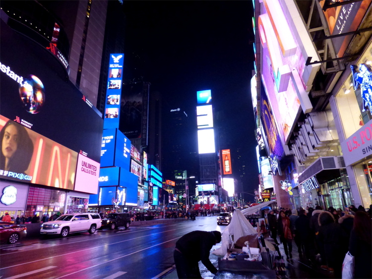 Advertising screens on Time Square casting red light on a mostly empty street