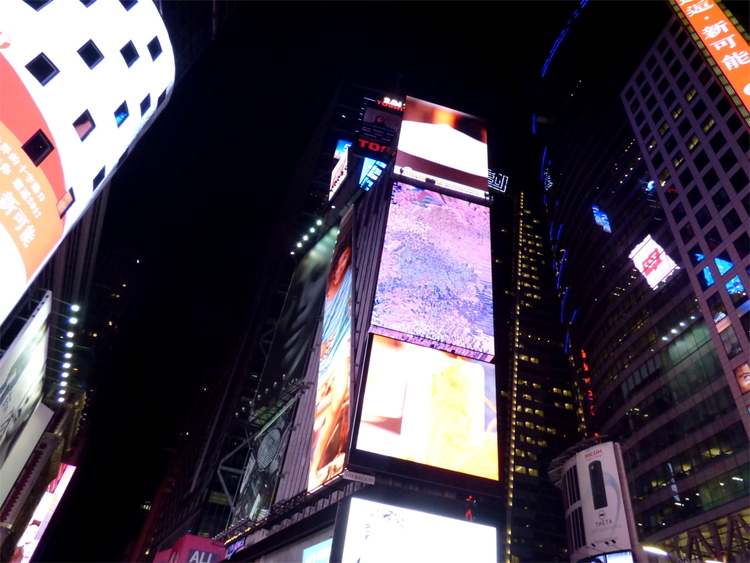 Some buildings covered in advertising screens, one of them showing a broken mess of colours instead of an advert