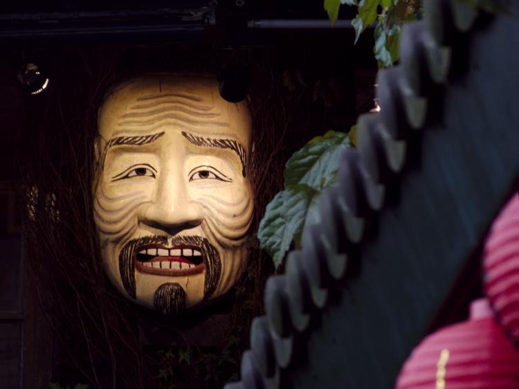 A grotesque mask of an old man's face with deep wrinkles hanging on the side of a building