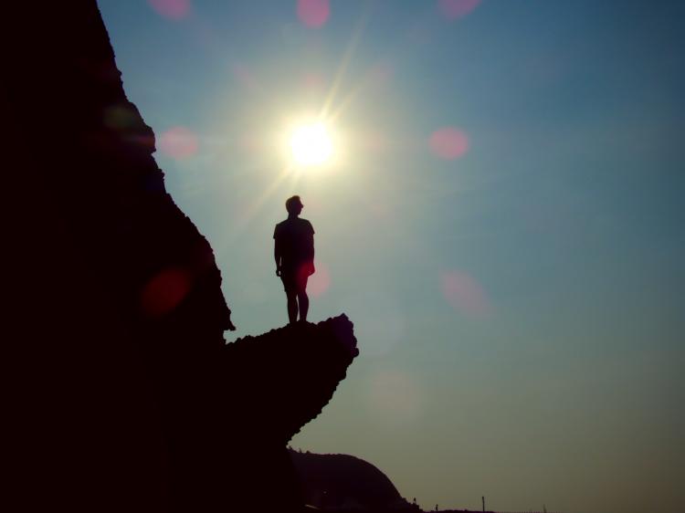 Jan's silhouette standing on a rock with the setting sun in the background