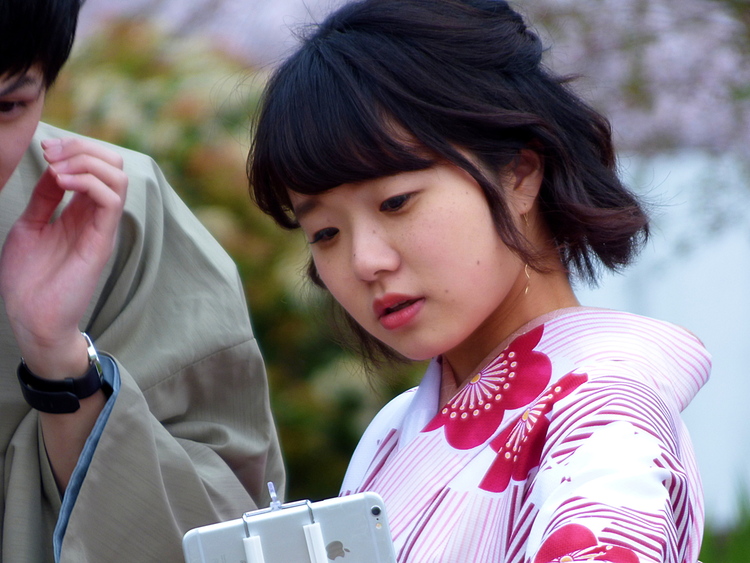 A woman in a red floral Kimono taking selfies with a man in traditional clothing