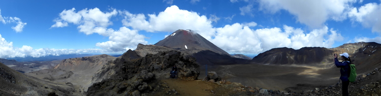 Panorama of a barren rocky mountain landscape with a hiking person taking pictures