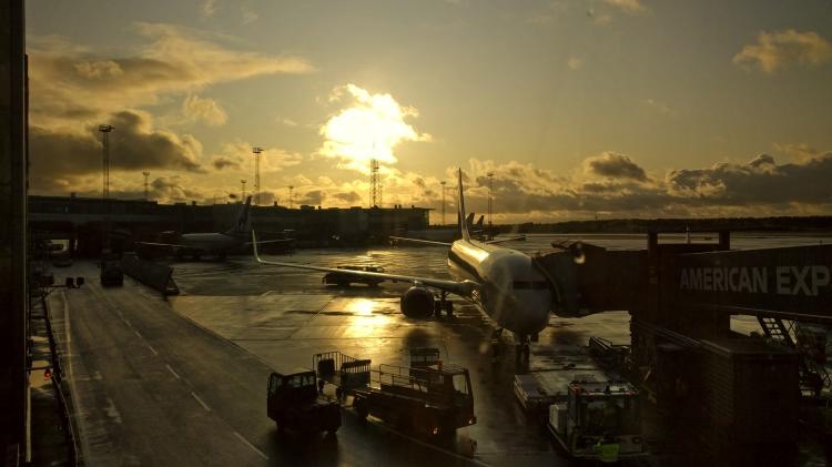 An air plane docked to a gangway illuminated by warm orange evening night with clouds on the horizon