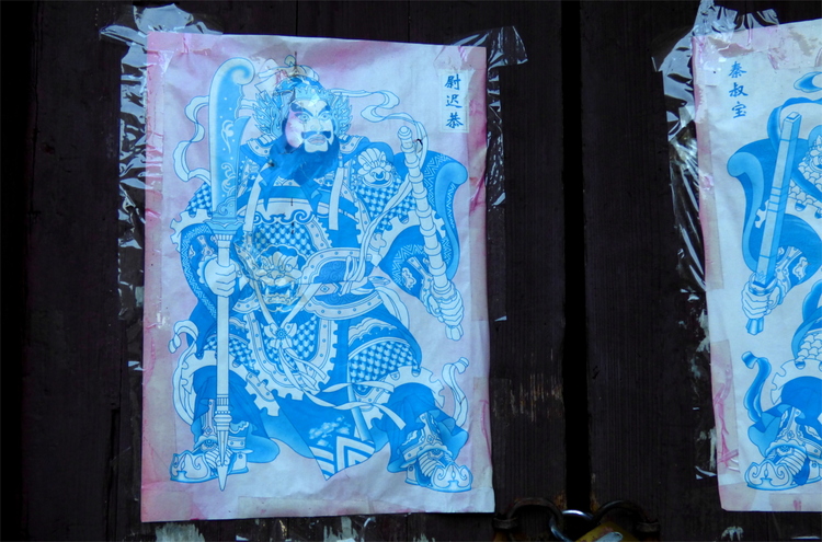 A faded, once red and blue poster showing an extravagantly clothed bearded figure holding a sword in one hand and a staff in the other