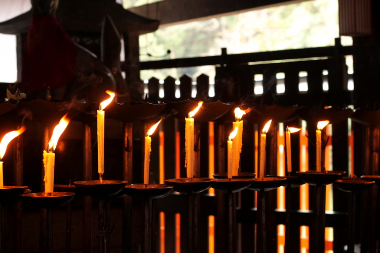 Many candles burning with tall, flickering flames