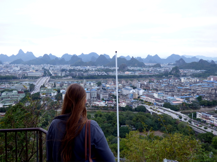 Katha looking down upon a city with mountains in the distance