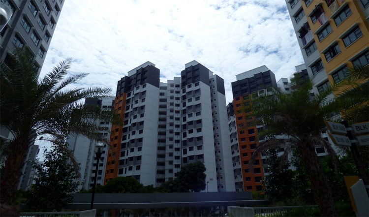 Modern high-rise residential buildings grouped around an open space with palm trees in the center